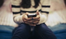 A teen holds a phone in her hands.