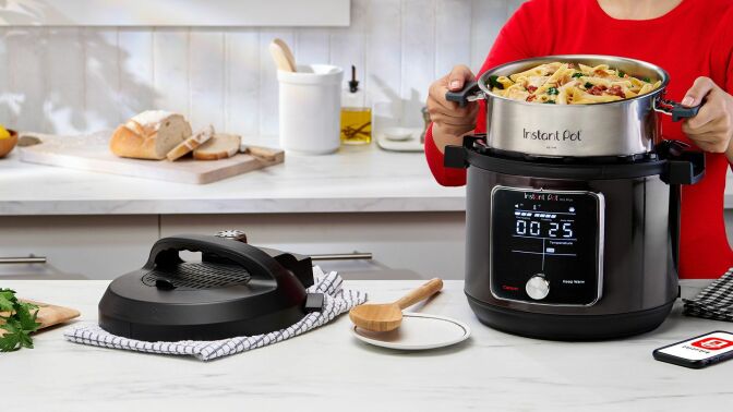Person lifting Instant Pot inner pot with oven mitts