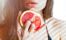 An image of a woman with her fingers in a citrus fruit.