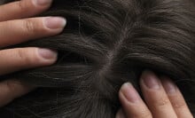 Close-up image of hair being parted in the middle with fingers. 