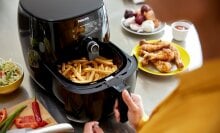 person cooking french fries in an air fryer
