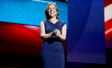 Susan Wojcicki from the knees up, smiling in a navy blue shift dress,