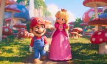 A man in overalls and a woman in a pink dress stroll though a mushroom field. 
