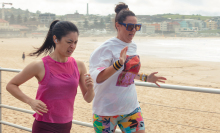 Two women jog along Bondi Beach.