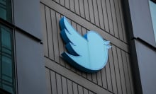 A blue Twitter bird logo on the side of a gray, concrete building. 
