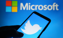 Microsoft logo hovering above Twitter logo on a mobile device