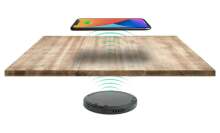 photograph of the wireless charger under a table with a phone pictured above the table 