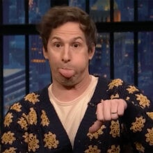 A man blows a raspberry while giving the thumbs down on a talk show.