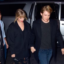 Taylor Swift and Joe Awlyn holding hands and looking down. 