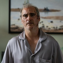 A man in grey pajamas with a bloody face.