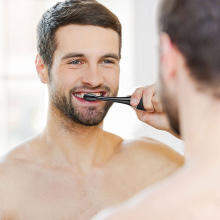 Man brushing his teeth in a mirror.