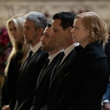The Roy family dressed all in black at the front row of a funeral in a large church.