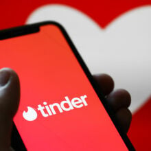 Someone holds an iPhone with the Tinder app open 