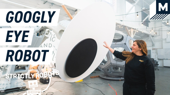 Dr. Madeline Gannon placing her hand on the googly eye equipped on the giant ABB robot