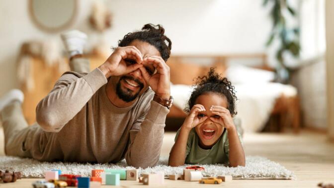 Happy African American family father with little son playing together, making binoculars with hands - stock photo