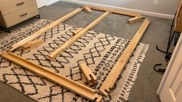 Unassembled Thuma bed frame laid out on a black and white rug
