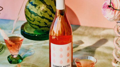bottle of pink wine on a table with watermelon and glasses
