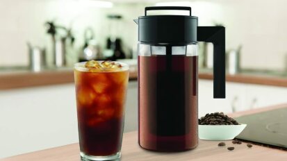 cold brew coffee maker next to a glass of iced cold brew