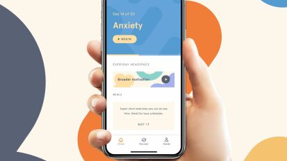 Person holding their phone with a Headspace subscription on a colorful background.