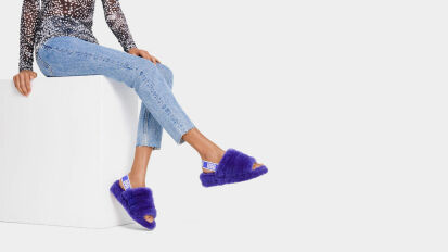 a person wearing fluffy purple Ugg slippers in front of a white background