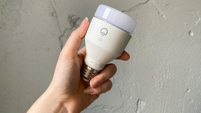 a close-up of a woman's hand holding a lifx smart bulb