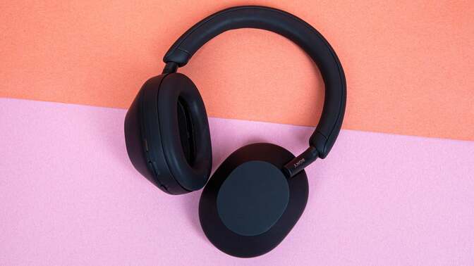 the Sony WH-1000XM5 headphones against a pink and orange background