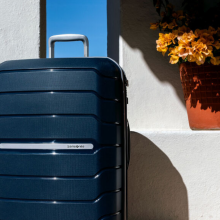 Blue Samsonite hardside suitcase with flower pot in background