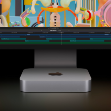 an m2 apple mac mini beneath an imac with a colorful display against a dark, shadowy background