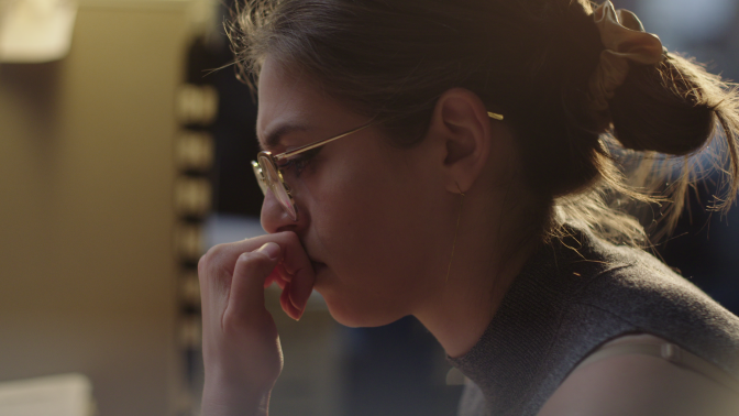 A profile shot of De Leon biting her fingernail while staring down at a screen.