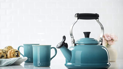 le creuset tea kettle in caribbean blue next to two matching mugs