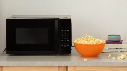 a microwave beside a bowl of popcorn on a countertop