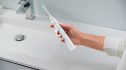 Person holding the Philips electric toothbrush over a sink.