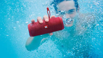 Person holding the JBL waterproof speaker underwater.