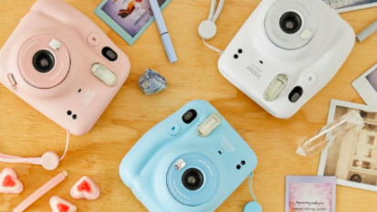 Fujifilm instant cameras of various colors on wooden table