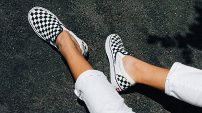 Feet wearing checkered slip-on vans