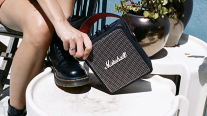 Person holding Marshall portable speaker on table