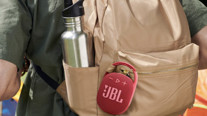A portable Bluetooth speaker from JBL clipped on a bag.