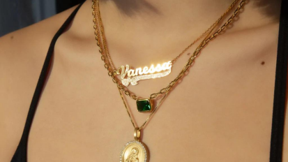 Person wearing three gold necklaces