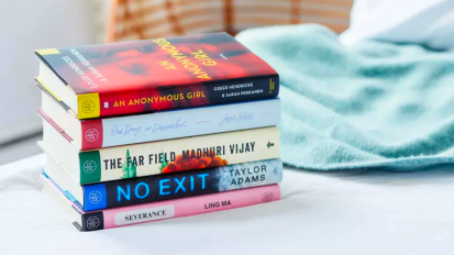 a stack of five books on a blanket next to a wicker basket