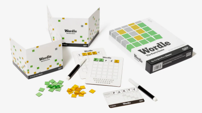 pieces of the wordle board game laid out on a flat surface next to its box
