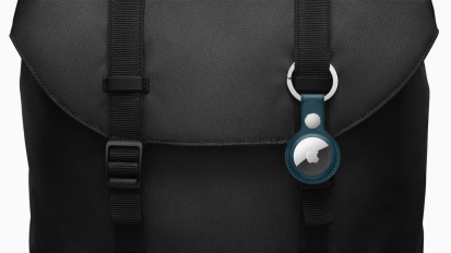 a close-up of an apple airtag on a keyring attached to a black backpack