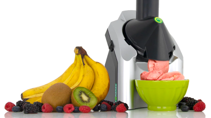 a yonanas machine in the process of making ice cream next to a pile of fruit